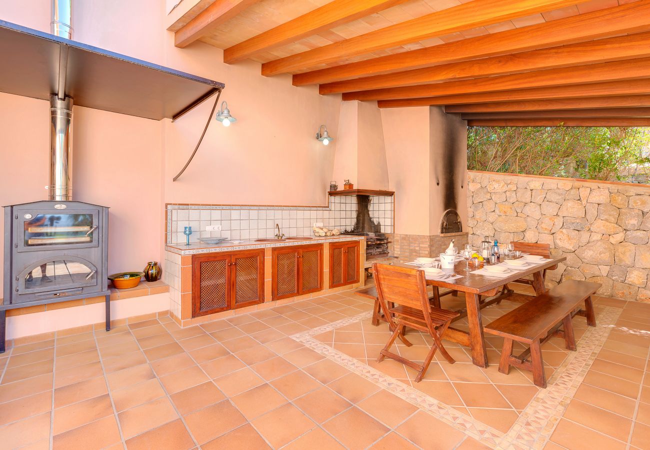 Covered dining area with a barbecue and a large table.
