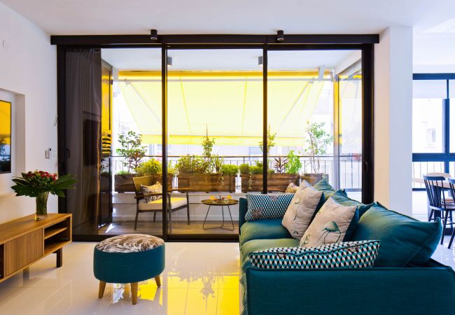 Beautiful sunny living room with a comfy sofa and a tv in apartment on Ben Yehuda st.