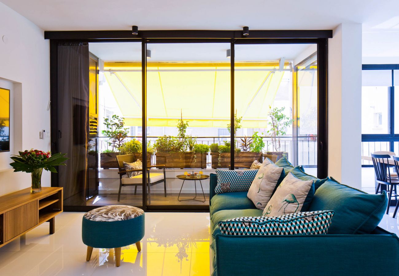 Beautiful sunny living room with a comfy sofa and a tv in apartment on Ben Yehuda st.