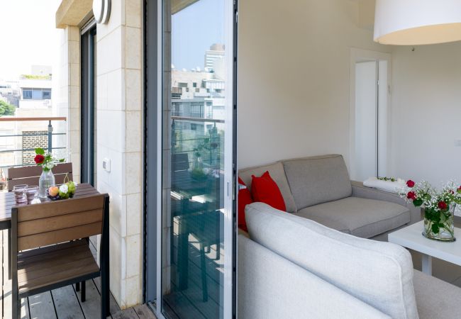 View of the furnished balcony and bright living room with a sofa in apartment on Ben Yehuda st.