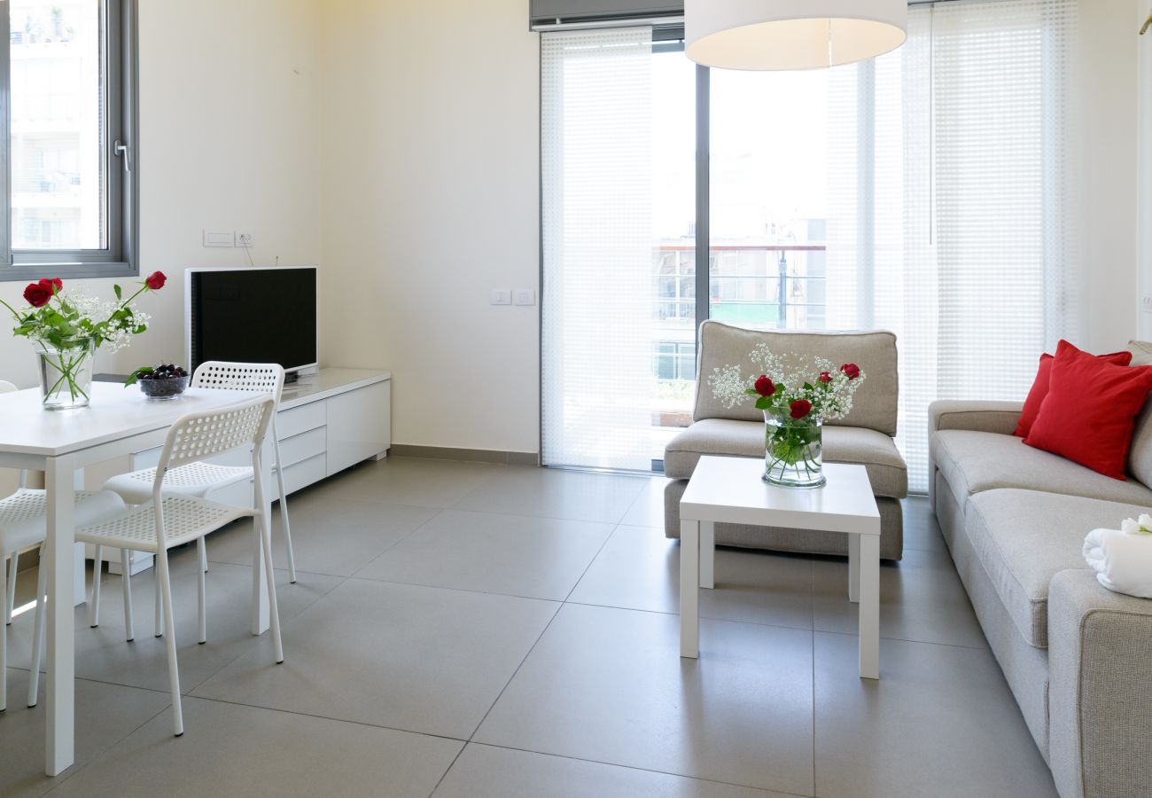 View of the bright living room with a comfy couch and dining area with a big table on Ben Yehuda st. 