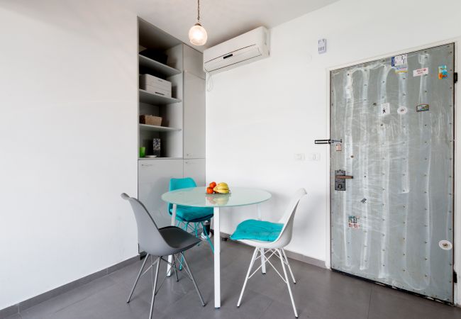 Modern dining area with a table and three chairs in apartment in Florentin 