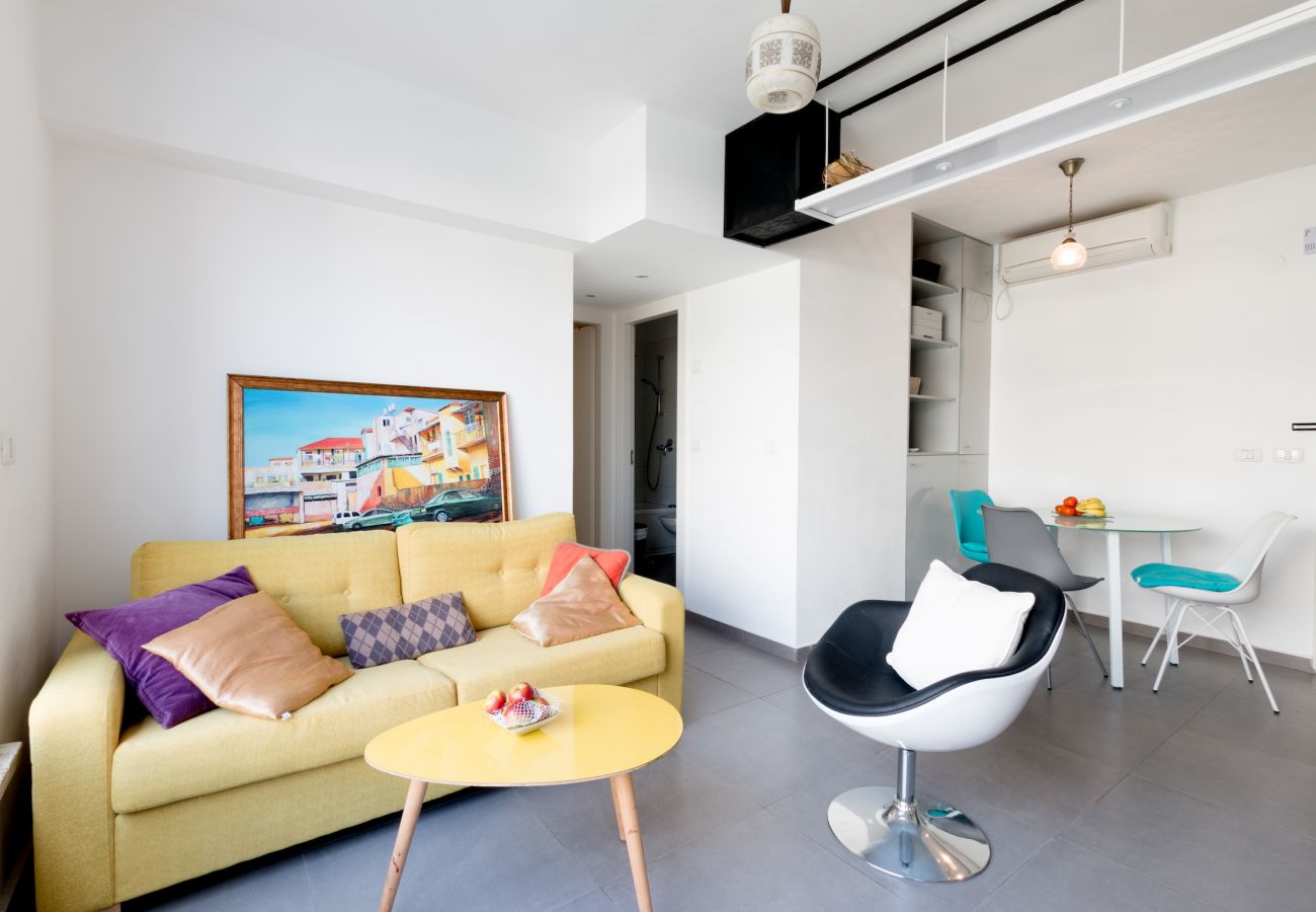 Colorful living room with comfy yellow sofa in apartment on Ben Yehuda st.